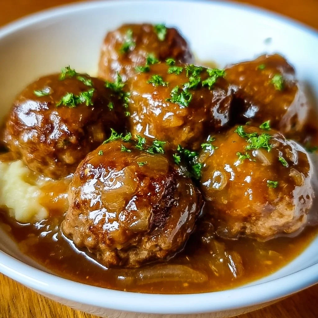 Crock Pot French Onion Meatballs served in a bowl, garnished with herbs.