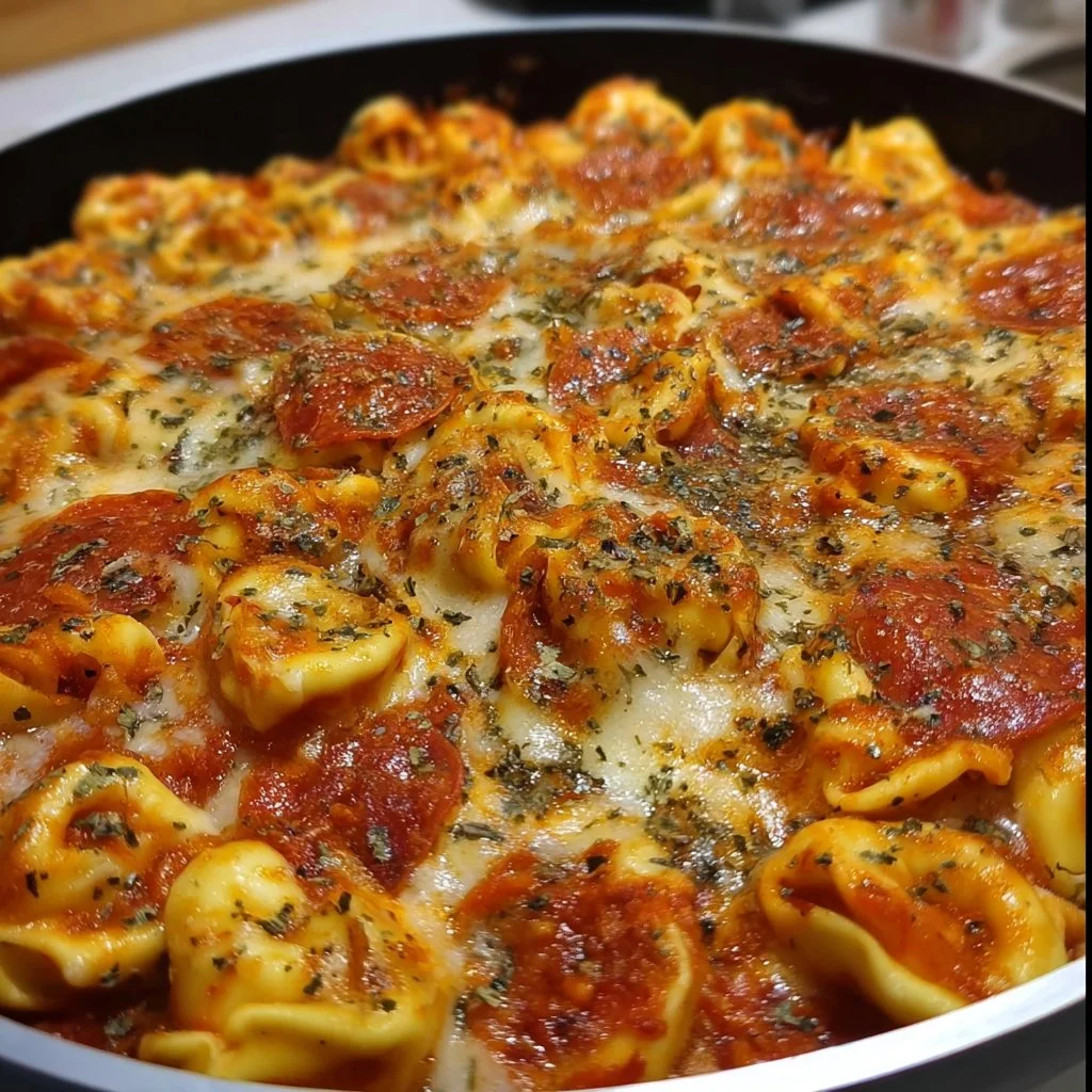 Delicious cheesy pizza tortellini served in a bowl, garnished with herbs.